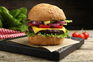 Delicious hamburger with patty and cheese on wooden table, closeup