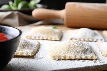 Uncooked ravioli and sauce on table, closeup