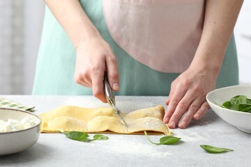Woman cutting ravioli at light table, closeup