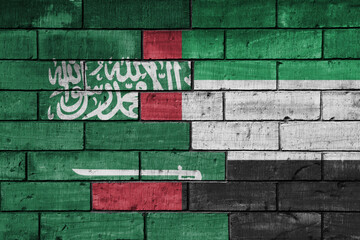 colourful painted big national flag of saudi arabia and flag of united arab emirates on a massive old brick wall background. concept