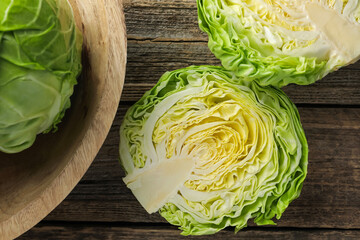 Halves of fresh cabbage on wooden table, flat lay
