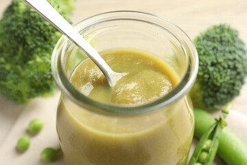 Baby food. Tasty puree in glass jar and ingredients on table, closeup
