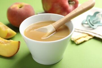 Baby food. Tasty puree in bowl and ingredients on green background, closeup