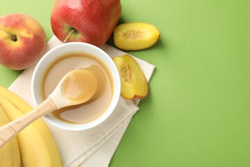 Baby food. Tasty puree in bowl and ingredients on green background, flat lay. Space for text