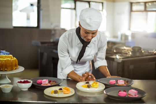 Naklejki Macarons, tarts and truffles resting on steel counter near bundt cake and raspberries