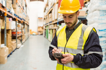 Man in high-vis vest scanning shelves using scanner with stylus in warehouse, copy space