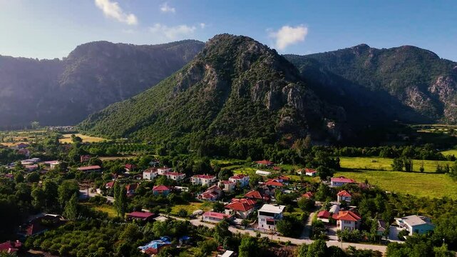Drone video capturing the serene landscape of Ortaca, with houses nestled amidst greenery and a majestic mountain backdrop