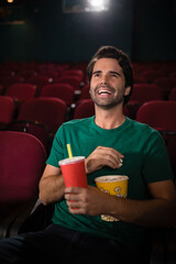 Naklejka premium Popcorn tub and disposable cup sitting on red cushioned theater seats, under soft projector glow