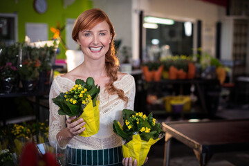 Yellow flowering plants are resting on wooden table in bright florist shop, with metal shelving