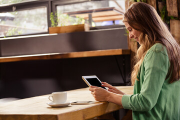 Tablet displaying content and resting on wooden counter beside smartphone and coffee cup in café © WavebreakMediaMicro