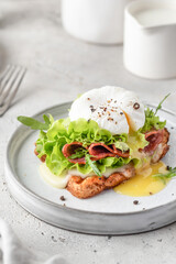 Toasted bread with poached egg, salad, cheese and ham on a plate on white kitchen background. Healthy breakfast, diet food