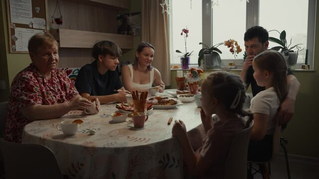 A family gathers around a table, enjoying a meal and conversation together.