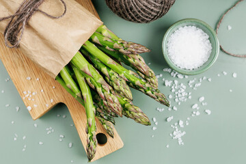 Flat lay of asparagus with sea salt and twine on green background