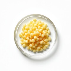 Candelilla wax SP-75 cosmetic ingredient on white laboratory table. Top view of granules in glass bowl, used in beauty industry for cosmetics production. Beauty, health, spa, wellness concept.