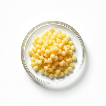 Candelilla wax SP-75 cosmetic ingredient on white laboratory table. Top view of granules in glass bowl, used in beauty industry for cosmetics production. Beauty, health, spa, wellness concept.