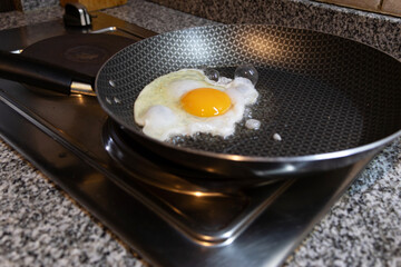 A still raw egg in the frying pan starting to fry