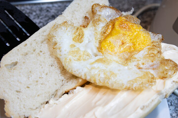 A fried egg inside a bun with mayonnaise photographed very close up