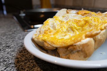 A well-fried egg inside a piece of bread photographed inside a plate and the kitchen environment in the background out of focus