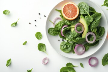 Fresh spinach salad with avocado, red onion, and orange slices on a white plate