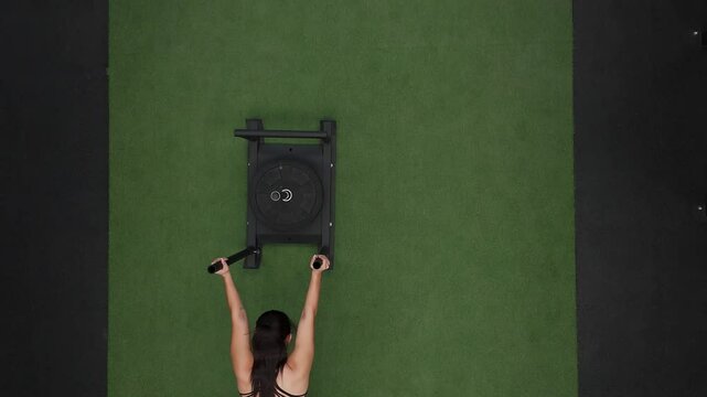 Mexican athlete performing sled push exercise in gym