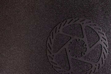 black bike brake disc on a black speckled background top view