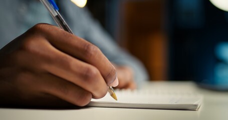 African American person working remotely and drafting project notes, organizing files and browsing...
