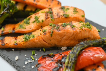 grilled salmon with vegetables on a slate plate, close-up