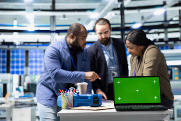 Fototapeta premium Coworkers brainstorming solutions with mockup display in solar plant, advancing industrial goals through collaboration and corporate responsibility. Team of engineers share insight.