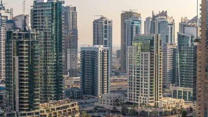Fototapeta premium Beautiful aerial view of Dubai Marina promenade and canal with floating yachts and boats before sunset in Dubai, UAE.