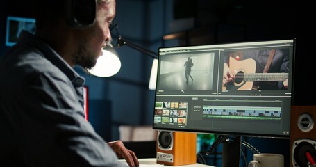 Young man video creator working on editing a movie montage project, multitasking with dual...