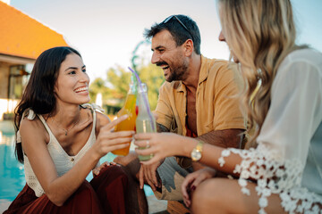 Friends toasting with refreshing drinks by the poolside