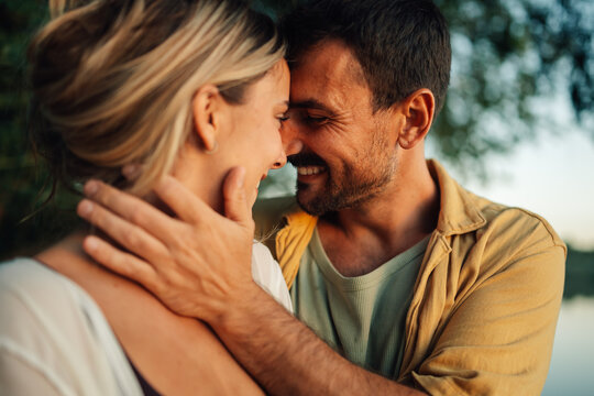 Happy couple sharing intimate moment at sunset by the lake