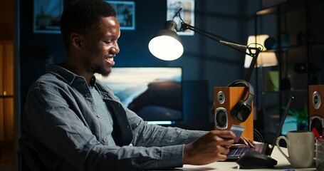 African american guy entering credit card details on internet page, preparing to pay on online...