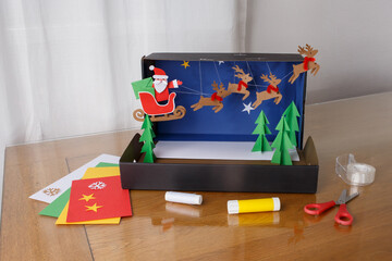 DIY Christmas scene with Santa and reindeer in paper craft box, great for children education, craft brands, holiday workshops, seasonal advertising, toy or stationery companies,