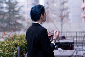 Young woman with wine glass standing outside in snowfall