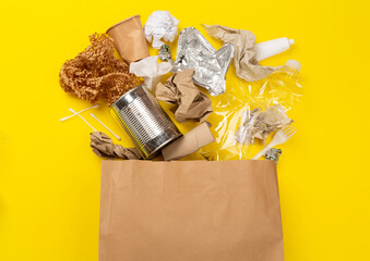 Bag with unsorted waste on color background, top view