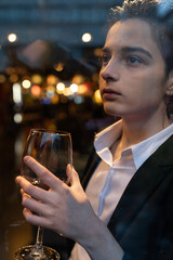 Young woman holding a wine glass in front of the window