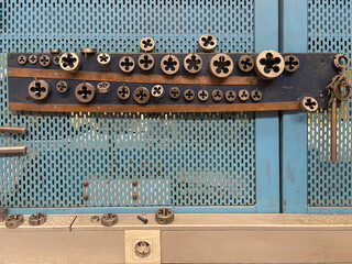 threading dies of different sizes and metrics in the tool panel of a machine tool shop