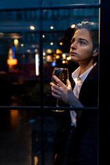 Young woman holding a wine glass in front of the window