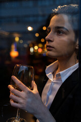 Young woman holding a wine glass in front of the window