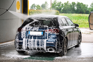 car in car wash covered in foam that dissolves dirt