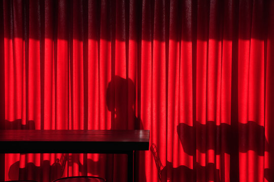 silhouette of a mysterious woman behind a red curtain
