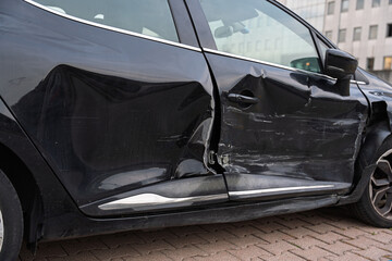 Close-up detail of car body damage from a collision, showing dent and paint scratches.