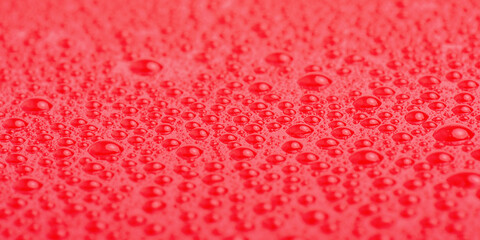 Texture of water drops on red plastic.