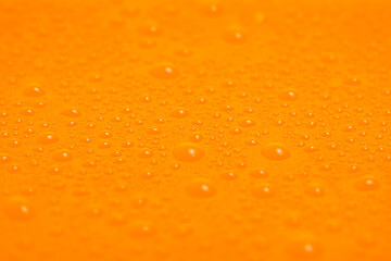 Texture of water drops on orange plastic.
