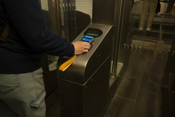 Smartphone hand payment activates subway turnstile with contactless technology in an underground transit station.