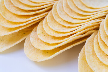 Close-up of stacked potato chips arranged in a curved pattern on a white surface. Ideal for snack food packaging, advertisements, or culinary-themed design projects