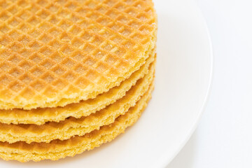 Stack of round golden waffle cookies neatly arranged on a white plate, isolated on white background. Ideal for dessert, snack, bakery, and breakfast themes