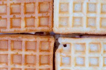 Close-up of four square waffles with different golden and light brown tones, showcasing crispy texture and pattern. Perfect for breakfast, food design, or bakery-themed visuals