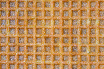 Extreme close-up of a golden waffle surface showing crispy texture and grid pattern. Perfect for backgrounds, food design, breakfast, and sweet snack themes.